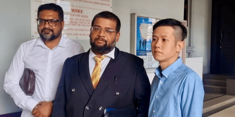 The accused’s lawyer (center), Sivahnanthan Ragava, together with the accused wearing blue, after this afternoon’s proceedings.